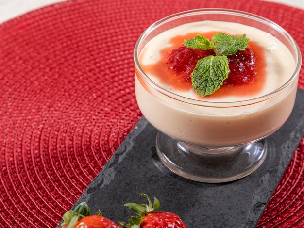 Mousse al limone in coppa di cristallo con topping di gelatina di fragole e menta.