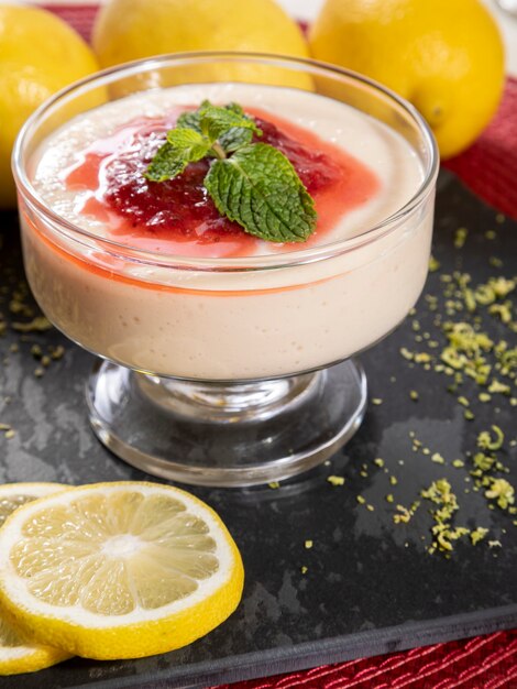 Mousse al limone in coppa di cristallo con topping di gelatina di fragole e menta.