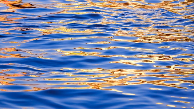 Movimento astratto della sfocatura della riflessione colorata della luce solare sulla superficie del mare all'ora del tramonto