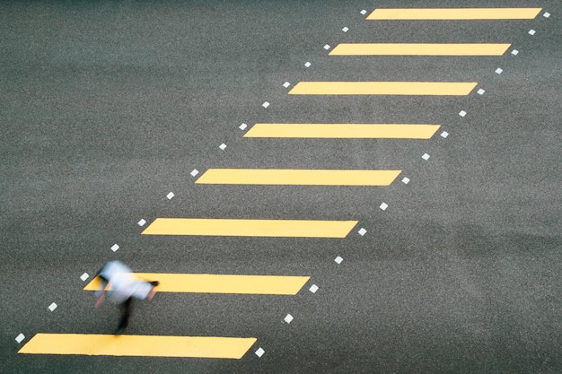 Movimento sfocato ad alto angolo di un uomo che cammina sul passaggio delle zebre