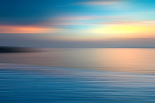 Movimento sfocato sfondo di rifrazione in acqua. Vista panoramica drammatica dell'Infinito tramonto sul mare al crepuscolo.