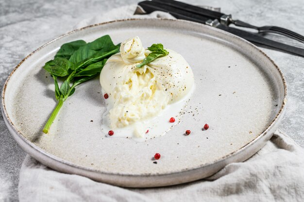 Mozzarella Burrata su un piatto bianco con foglie di basilico. Vista dall'alto