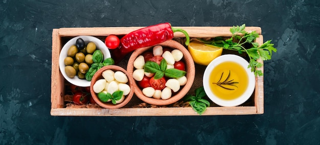 Mozzarella pomodorini basilico foglie olio olive in una scatola di legno Vista dall'alto Spazio libero per il testo