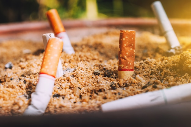 Mozziconi di sigaretta in vasi di sabbia, concetto di non fumare