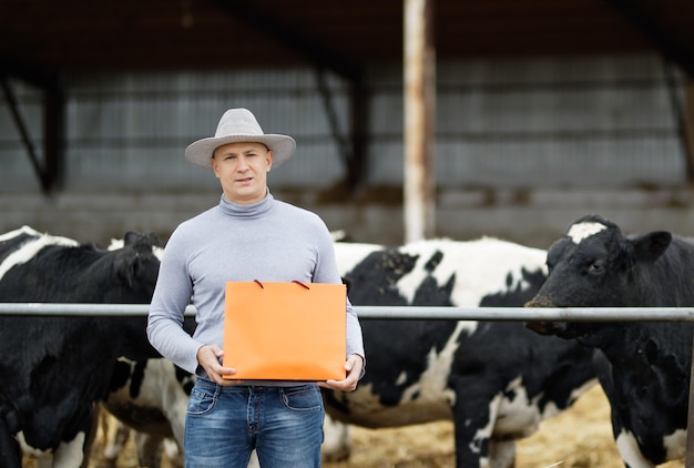 Mucche del atfarm del ritratto dell'agricoltore che mostrano un prodotto