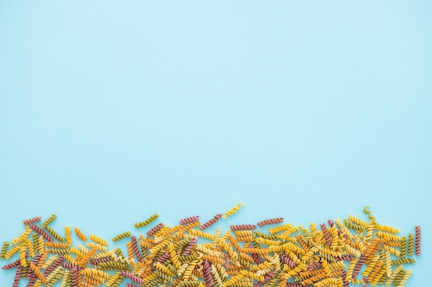 Mucchi di pasta vari colori farfalle di pasta su sfondo blu vista dall'alto