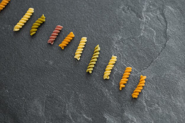 Mucchi di pasta vari colori farfalle di pasta su sfondo scuro vista dall'alto