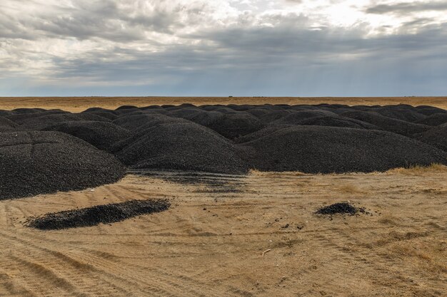 Mucchi di vecchio asfalto nella steppa dopo la riparazione della strada, Kazakistan.