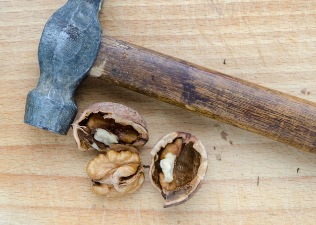 Mucchio delizioso e sano di noci su una tavola di legno con un martello