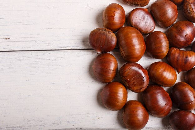 Mucchio delle castagne dolci su fondo di legno bianco