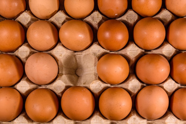 Mucchio delle uova di gallina in vassoio di carta sulla tavola di legno. Vista dall'alto