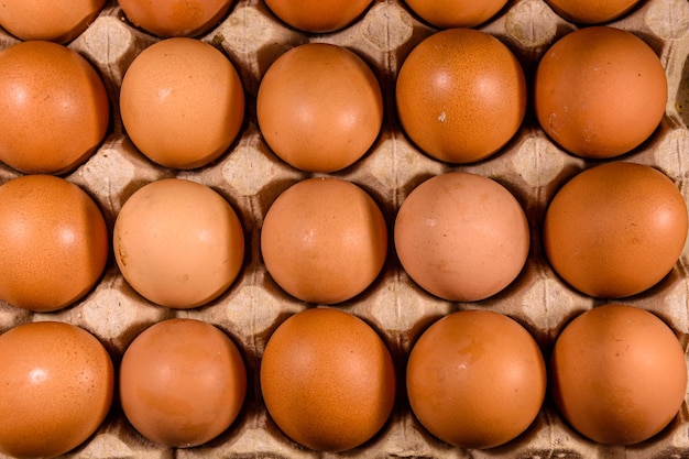 Mucchio delle uova di gallina nel vassoio della carta sul tavolo di legno Vista dall'alto