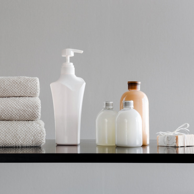 Mucchio di asciugamani, bottiglie con shampoo, balsamo, latte per doccia e sapone fatto a mano.