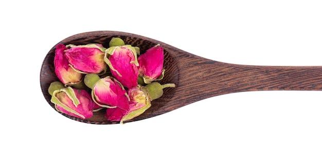 Mucchio di boccioli di rose di tè essiccate in un cucchiaio di legno isolato su sfondo bianco ritaglio di tè di fiori di rosa