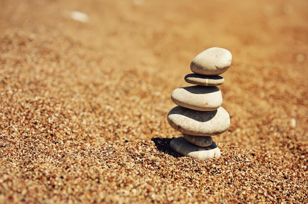 Mucchio di cairn da pietre sulla spiaggia di sabbia vicino al concetto di armonia e stabilità del mare