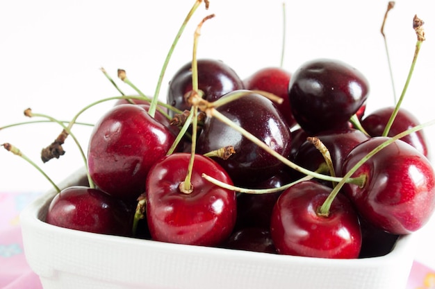 Mucchio di ciliegie appena raccolte in cestino bianco.