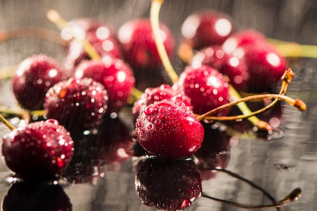 Mucchio di ciliegie con foglie e gocce d'acqua sul tavolo di pietra nera Ciliege mature mature