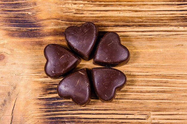 Mucchio di cioccolatini a forma di cuore su un tavolo di legno. Vista dall'alto. Concetto di San Valentino