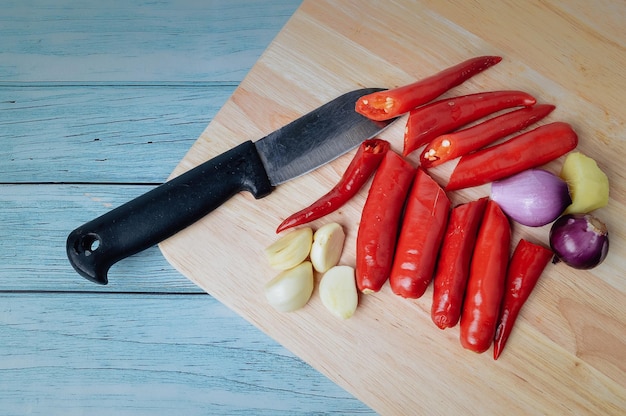 Mucchio di cipolle e aglio di peperoncini rossi freschi sul tagliere di legno