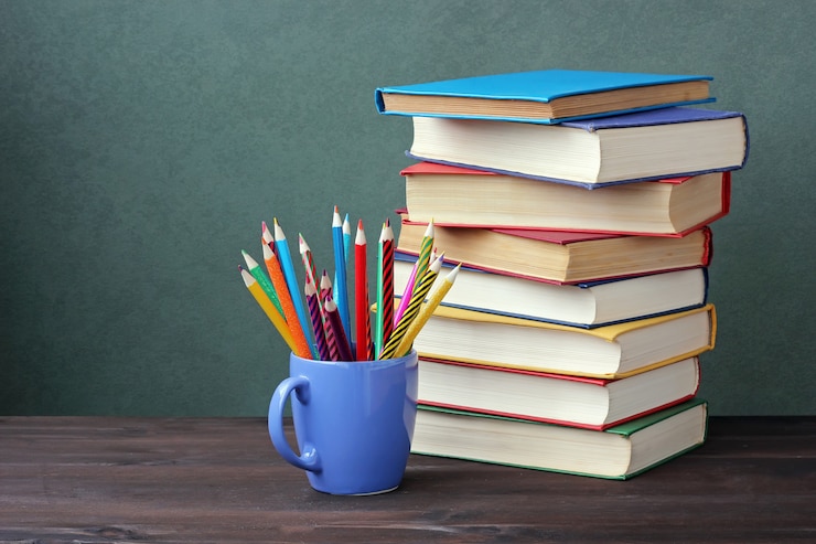Foto mucchio di libri con copertine di colore e matite colorate in una tazza su un tavolo di legno