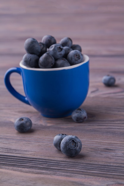 Mucchio di mirtilli in una tazza verticale di ceramica blu