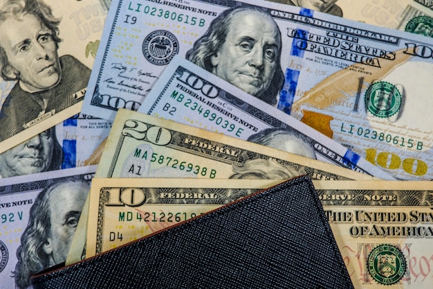 Mucchio di molte banconote in dollari USA con portafoglio nero