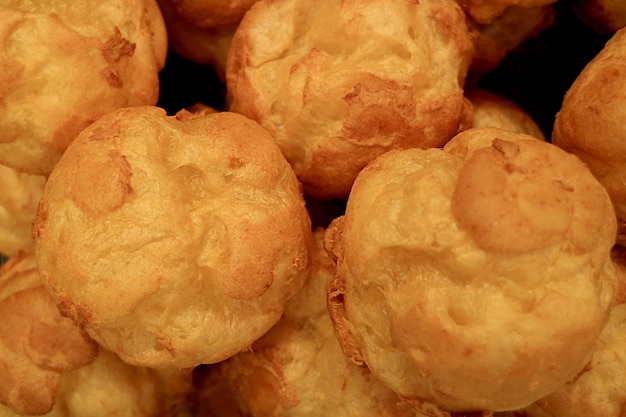 Mucchio di palline di pasta choux francesi appena sfornate durante il raffreddamento dell'alba prima del ripieno di crema