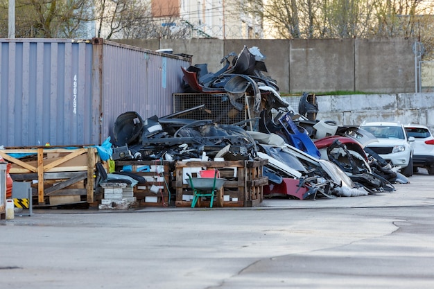 Mucchio di paraurti di plastica rotti dietro una concessionaria di automobili e un centro di assistenza