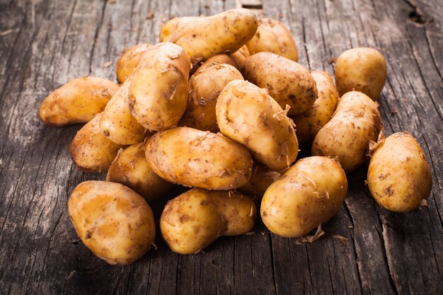 Mucchio di patate giovani su uno sfondo di legno