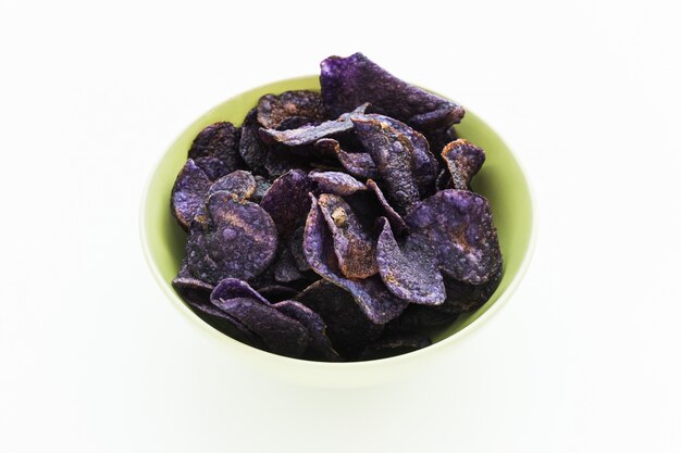 Mucchio di patatine viola su sfondo bianco