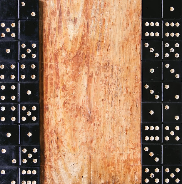 Mucchio di piastrelle domino nere vintage su tavola di legno.