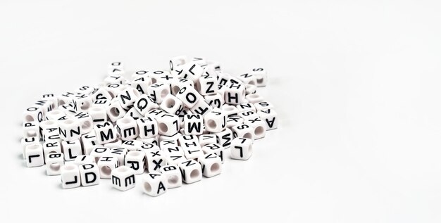 Mucchio di piccole perline cubo bianco con varie lettere sparse a bordo, spazio per il testo a destra