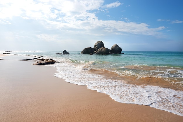 Mucchio di pietre nell'oceano vicino alla spiaggia sabbiosa