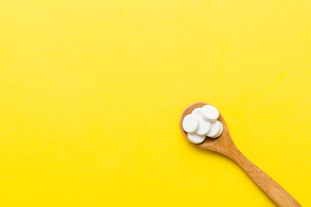 Mucchio di pillole bianche su sfondo colorato Compresse sparse su un tavolo Pila di capsule di gelatina morbida rossa Concetto di vitamine e integratori alimentari