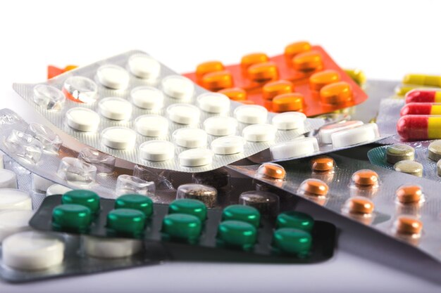 Mucchio di pillole multicolori con vesciche che giacciono su uno sfondo bianco
