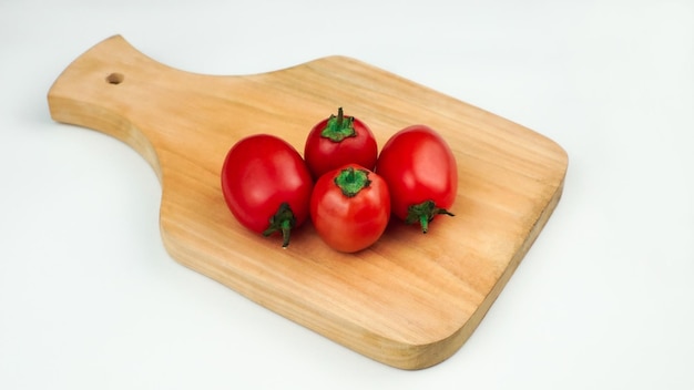 Mucchio di pomodori su una tavola di legno Pomodori freschi organici isolati su bianco