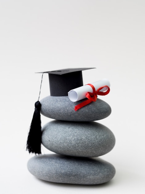 Mucchio di rocce con cappello di laurea e diploma