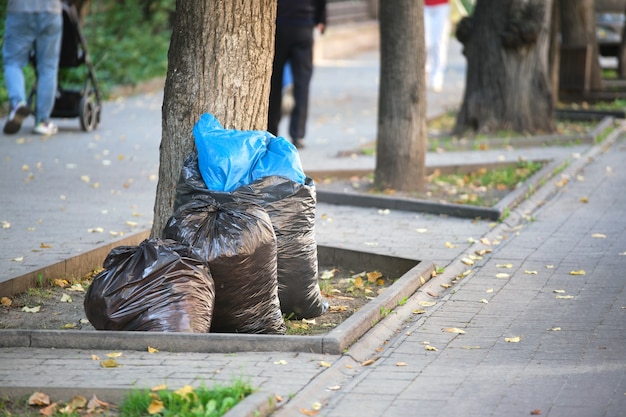 Mucchio di sacchi della spazzatura neri pieni di rifiuti lasciati per il ritiro sul lato della strada. Smaltimento dei rifiuti concetto.