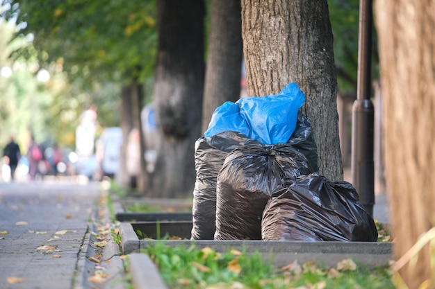 Mucchio di sacchi neri pieni di rifiuti lasciati per il ritiro sul lato della strada Concetto di smaltimento dei rifiuti