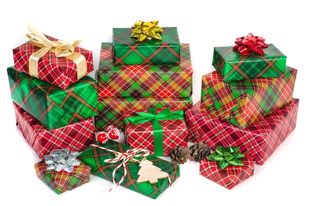 Mucchio di scatole di Natale con regali in carta a scacchi verde e rossa con fiocchi su sfondo bianco