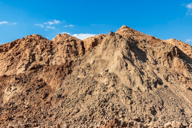Mucchio di terra, sabbia e argilla in cantiere contro il cielo Lavori di sterro in cantiere
