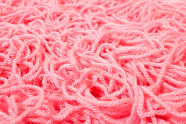 Mucchio di un filato per maglieria aggrovigliato rosa di lana.
