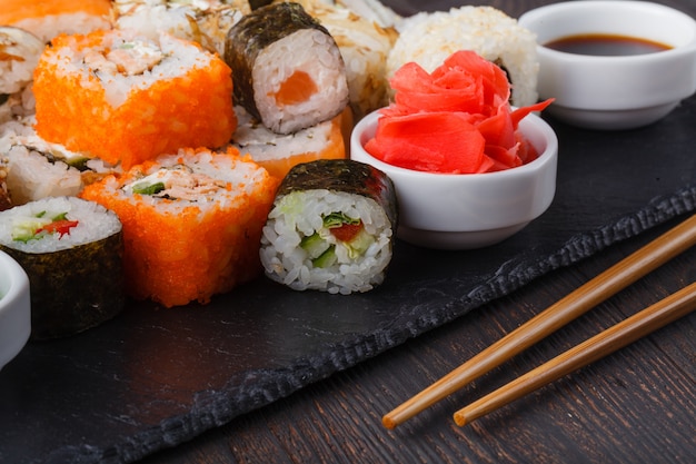 Mucchio di vari tipi di sushi servito su pietra nera