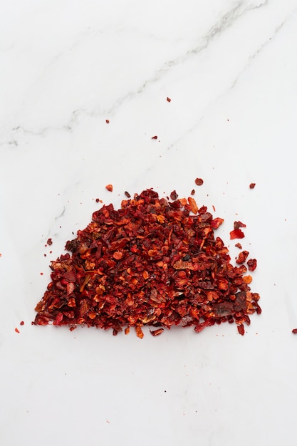 Mucchio schiacciato del peperone di roja di pimienta dalla cima su fondo bianco. Mucchio di fiocchi di peperoncino, peperoncino rosso macinato paprika Fiocchi di peperoncino fresco e tritato. Concetto di cucina, spezie e cucina.