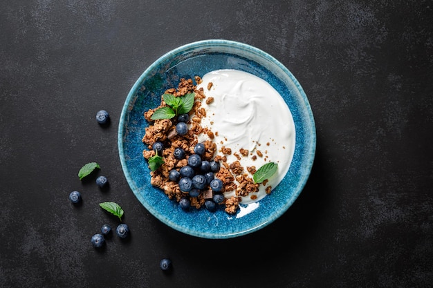 Muesli al cioccolato con yogurt bianco e mirtilli freschi in una ciotola cibo sano per colazione vista dall'alto