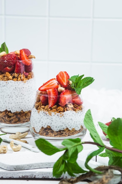 Muesli con yogurt chia e fragole in un bicchiere su sfondo bianco