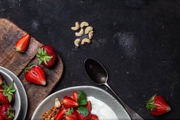 Muesli con yogurt e fragole in un piatto su uno sfondo scuro