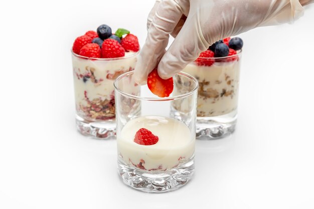 Muesli con yogurt e frutti di bosco in un bicchiere su sfondo bianco