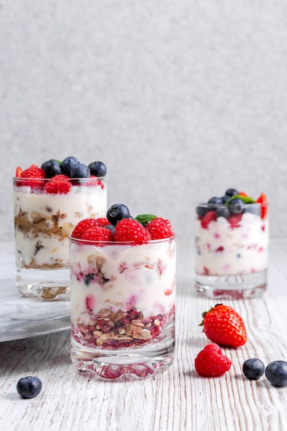 Muesli con yogurt e frutti di bosco in un bicchiere su sfondo bianco