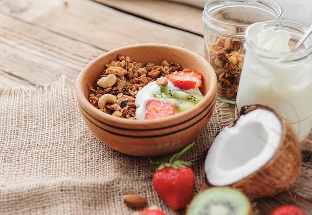 Muesli con yogurt greco e frutta su fondo di legno in stile rustico